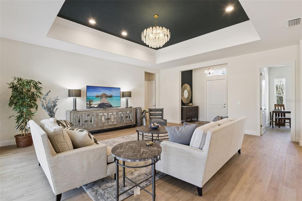 A living room features a tray ceiling with a dark interior and a crystal chandelier — 4044 PINNACLE PLACE, LADY LAKE, FL