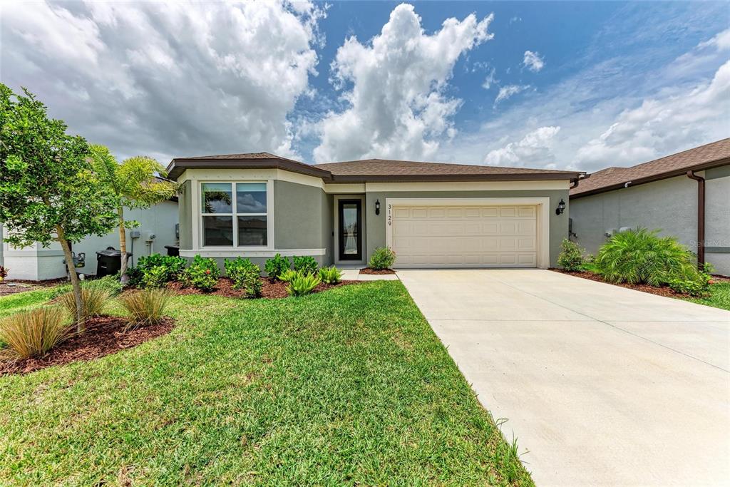A single-story house with a gray exterior, a two-car garage, and a landscaped front yard — 3129 61ST TERRACE E, ELLENTON, FL