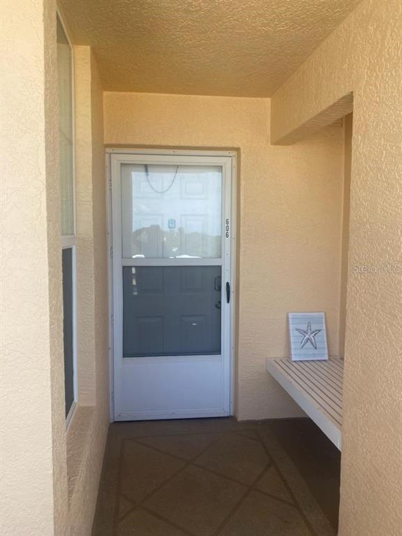 A covered entryway features a white storm door, a built-in bench, and a starfish decoration — 4460 FAIRWAYS BOULEVARD UNIT 606, BRADENTON, FL
