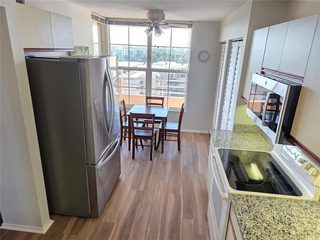 A kitchen with stainless steel appliances, granite countertops, and a dining area by a window — 4460 FAIRWAYS BOULEVARD UNIT 606, BRADENTON, FL