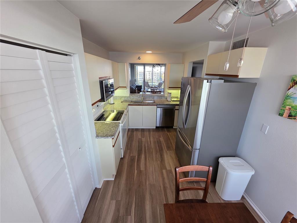 A kitchen with stainless steel appliances, granite countertops, and light cabinetry overlooks a balcony — 4460 FAIRWAYS BOULEVARD UNIT 606, BRADENTON, FL