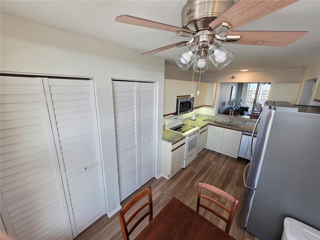 A kitchen with light cabinets, stainless steel appliances, and wood-look flooring sits near a dining area — 4460 FAIRWAYS BOULEVARD UNIT 606, BRADENTON, FL
