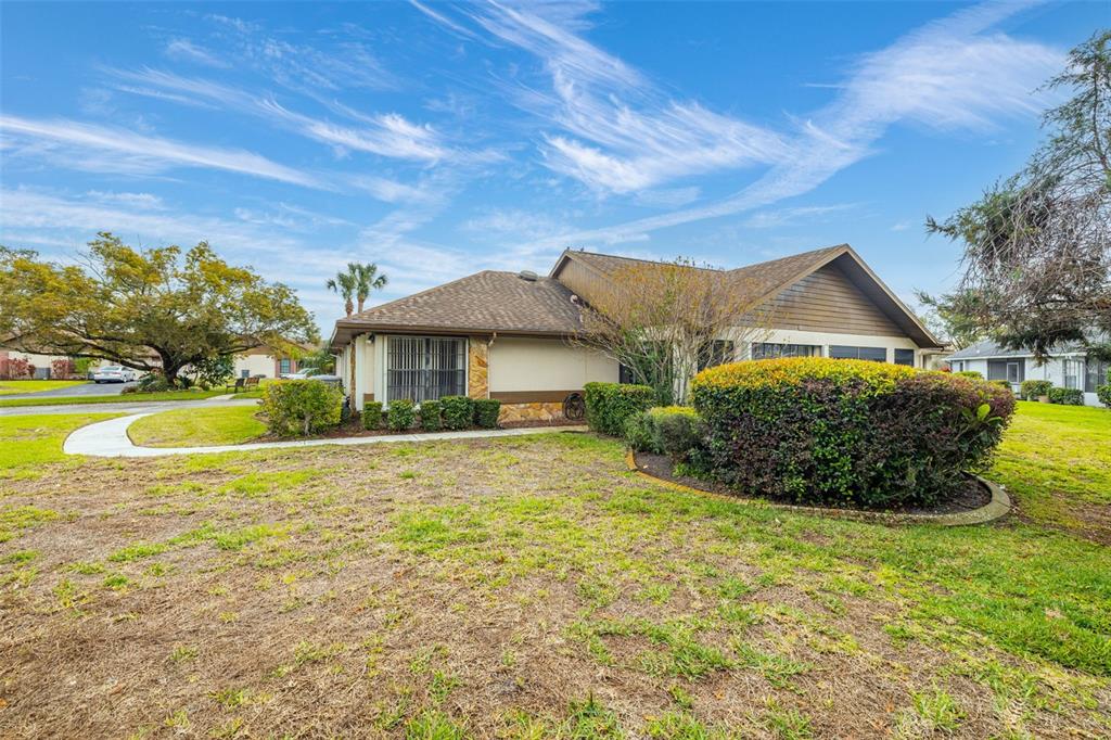 A single-story house with a brown shingled roof and a large front yard — 7703 ROCKVILLE COURT, NEW PORT RICHEY, FL
