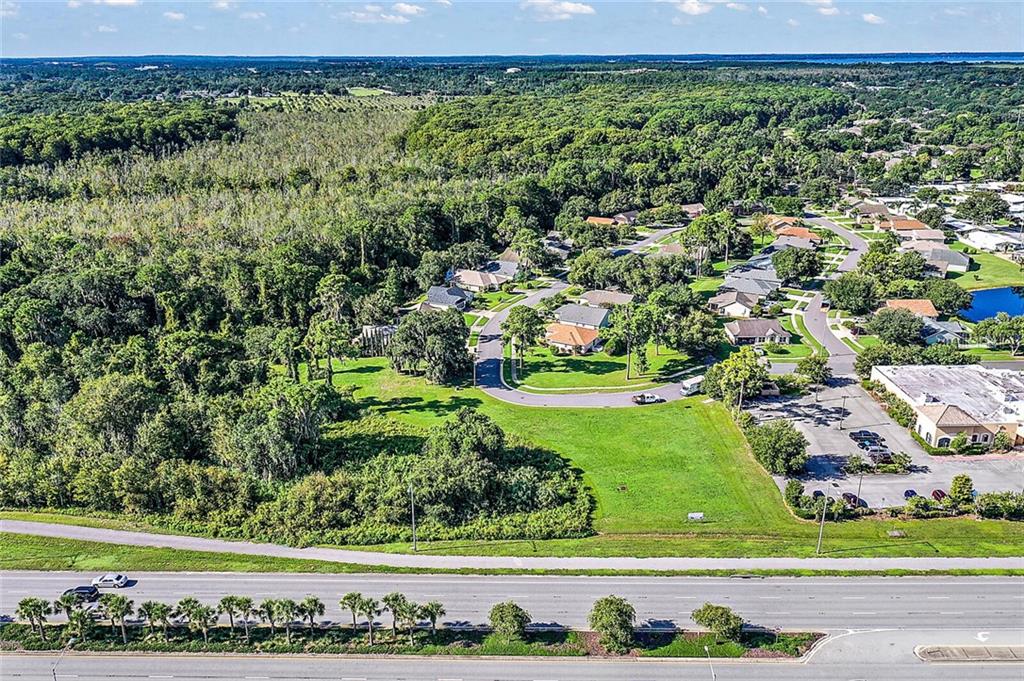 An aerial view shows a vacant grassy lot adjacent to a residential neighborhood and highway — 2000 VINDALE RD  & US HWY 441, TAVARES, FL