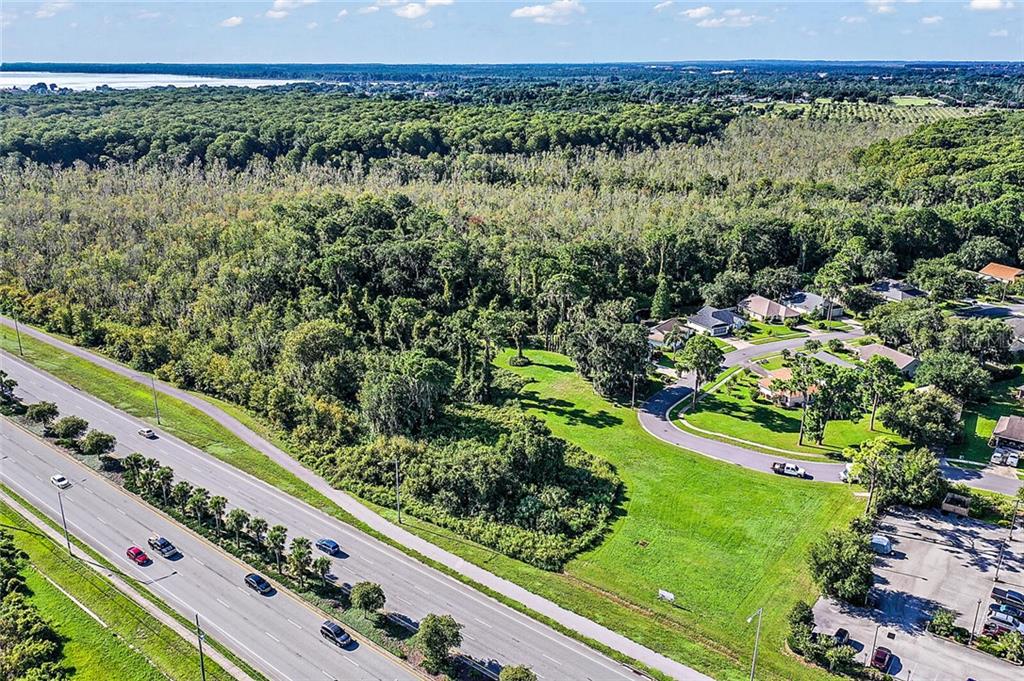 An aerial view shows a vacant grassy lot bordered by a highway and a residential neighborhood — 2000 VINDALE RD  & US HWY 441, TAVARES, FL