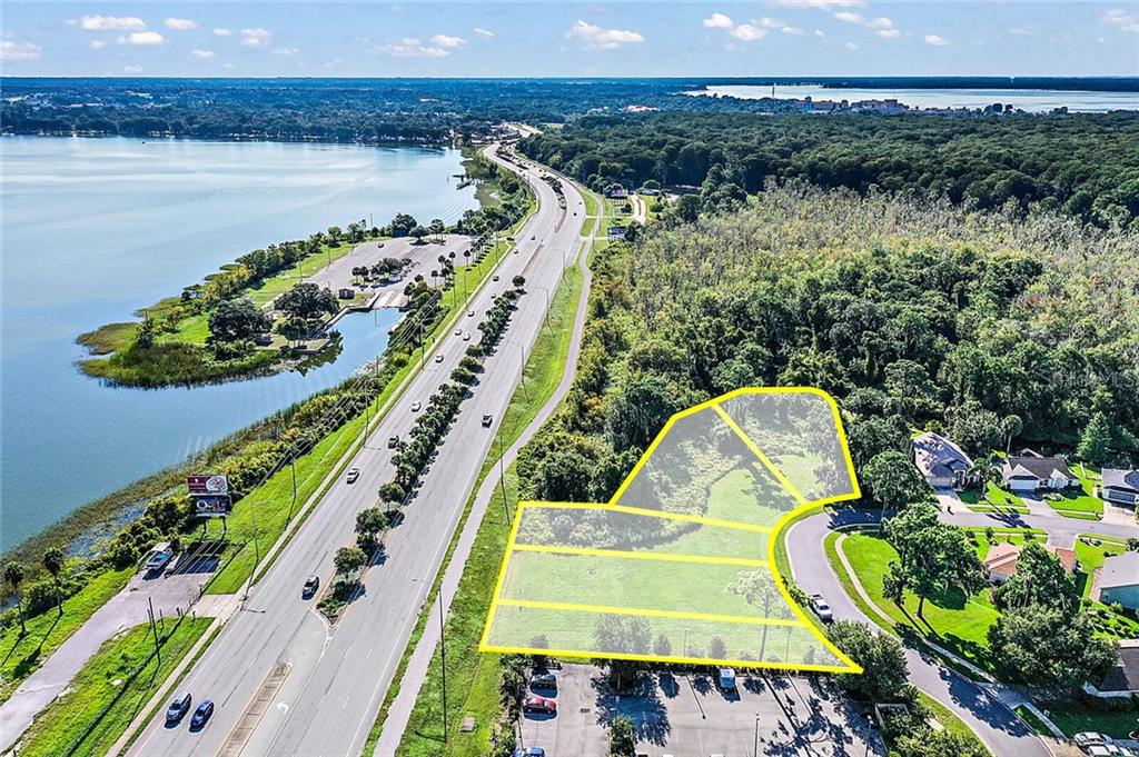 An aerial view shows a vacant, highlighted land parcel situated between a highway and houses — 2000 VINDALE RD  & US HWY 441, TAVARES, FL