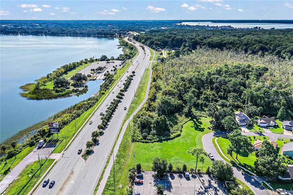 An aerial view shows a highway running alongside a large lake and dense forest area — 2000 VINDALE RD  & US HWY 441, TAVARES, FL