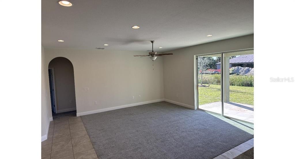 A living room with gray carpet, recessed lighting, a ceiling fan, and sliding glass doors — 2573 TULSA AVENUE, NORTH PORT, FL