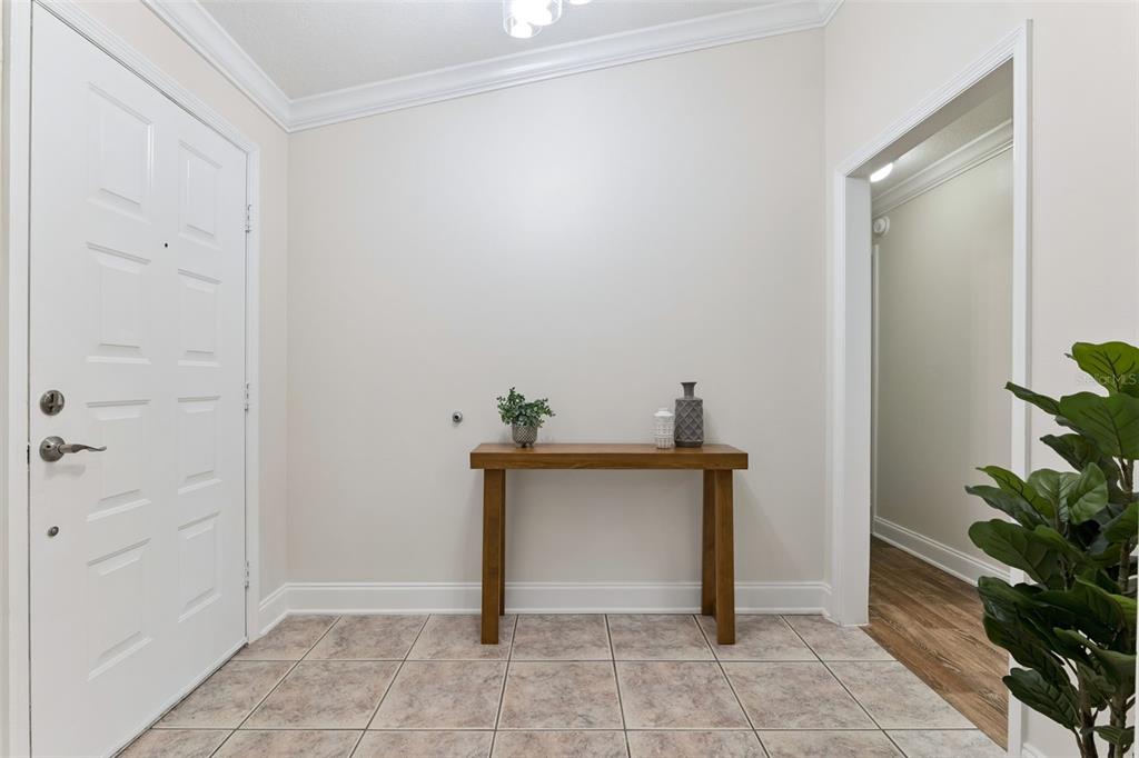 An entryway with a white door, tiled floor, and a wooden console table against a wall — 2450 DRESDEN TRAIL, APOPKA, FL
