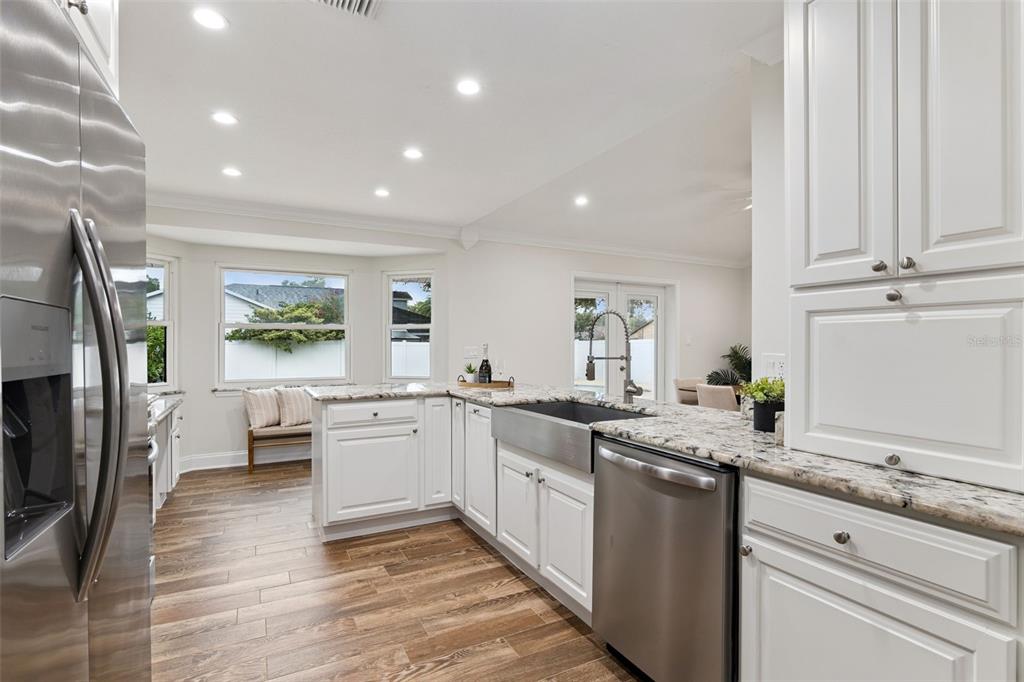 A kitchen features white cabinetry, granite countertops, stainless steel appliances, and wood-look tile flooring — 2450 DRESDEN TRAIL, APOPKA, FL