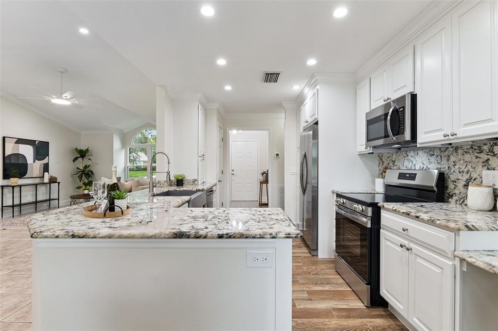 A kitchen with white cabinets, granite countertops, stainless steel appliances, and an island — 2450 DRESDEN TRAIL, APOPKA, FL