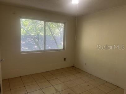 An empty bedroom features light-colored walls, a large window, and beige tile flooring — 543 DIVISION STREET UNIT 4, DAYTONA BEACH, FL