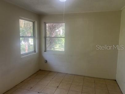 An empty room features light-colored walls, tiled flooring, and two windows overlooking outdoor greenery — 543 DIVISION STREET UNIT 4, DAYTONA BEACH, FL
