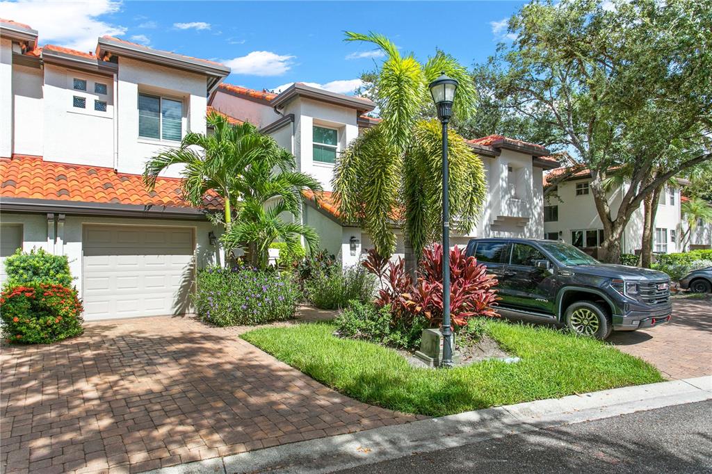 A two-story townhouse with a garage, brick paver driveway, and palm trees in the front — 1116 SHIPWATCH CIRCLE, TAMPA, FL