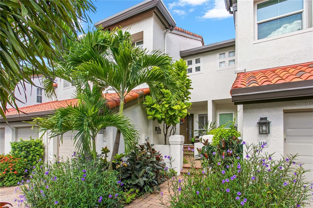 The exterior of a two-story townhouse features white stucco walls, a tiled roof, and landscaping — 1116 SHIPWATCH CIRCLE, TAMPA, FL