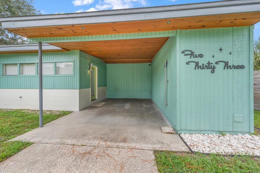 A teal-colored house exterior features a concrete carport with a natural wood-paneled ceiling — 533 BROXBURN AVENUE, TEMPLE TERRACE, FL