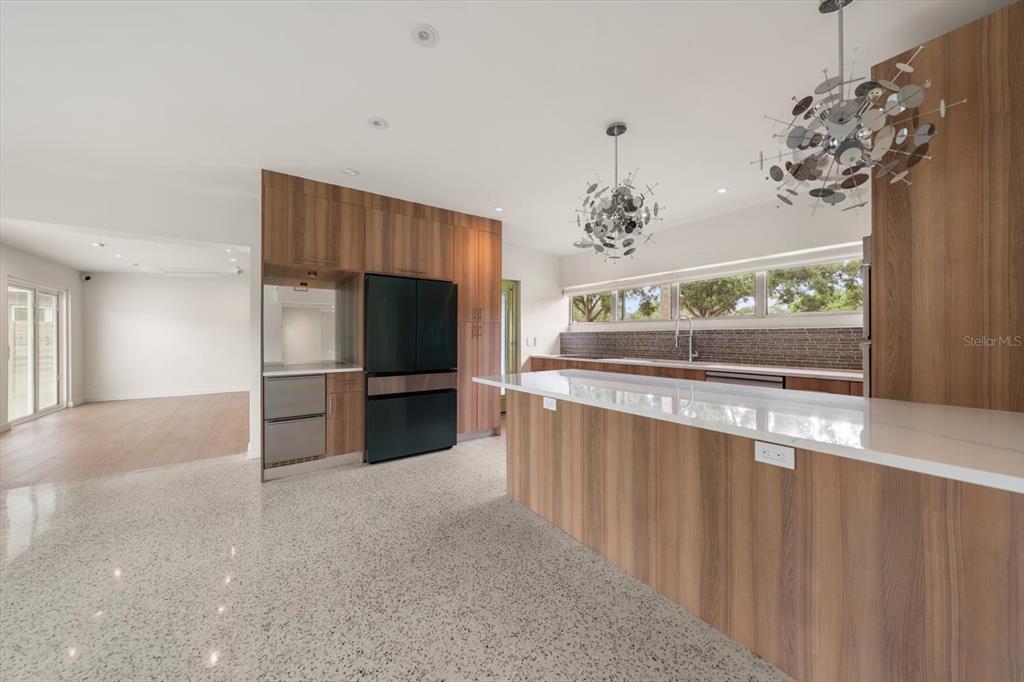 A modern kitchen features wood cabinetry, a large island with a white countertop, and terrazzo flooring — 533 BROXBURN AVENUE, TEMPLE TERRACE, FL