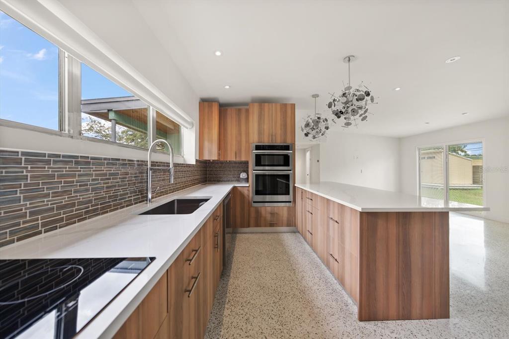 A modern kitchen features wood-grain cabinets, white countertops, a tiled backsplash, and a terrazzo floor — 533 BROXBURN AVENUE, TEMPLE TERRACE, FL