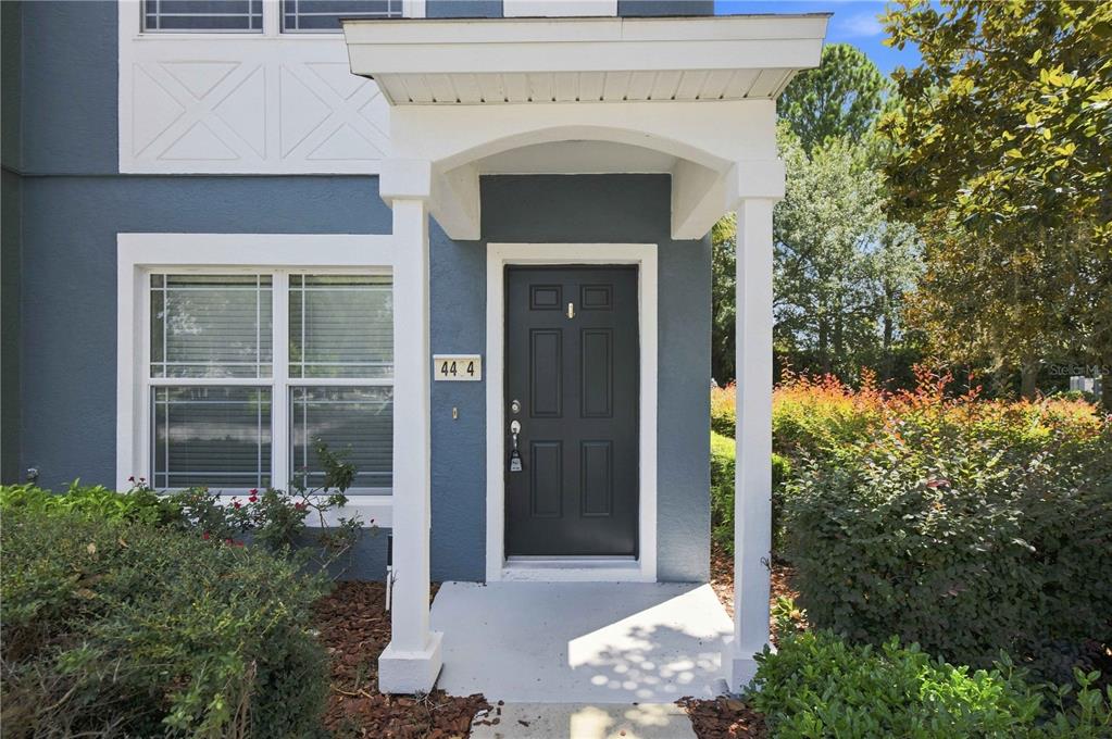The exterior of a home features a dark front door under a white covered porch — 4434 SW 49TH AVENUE, OCALA, FL
