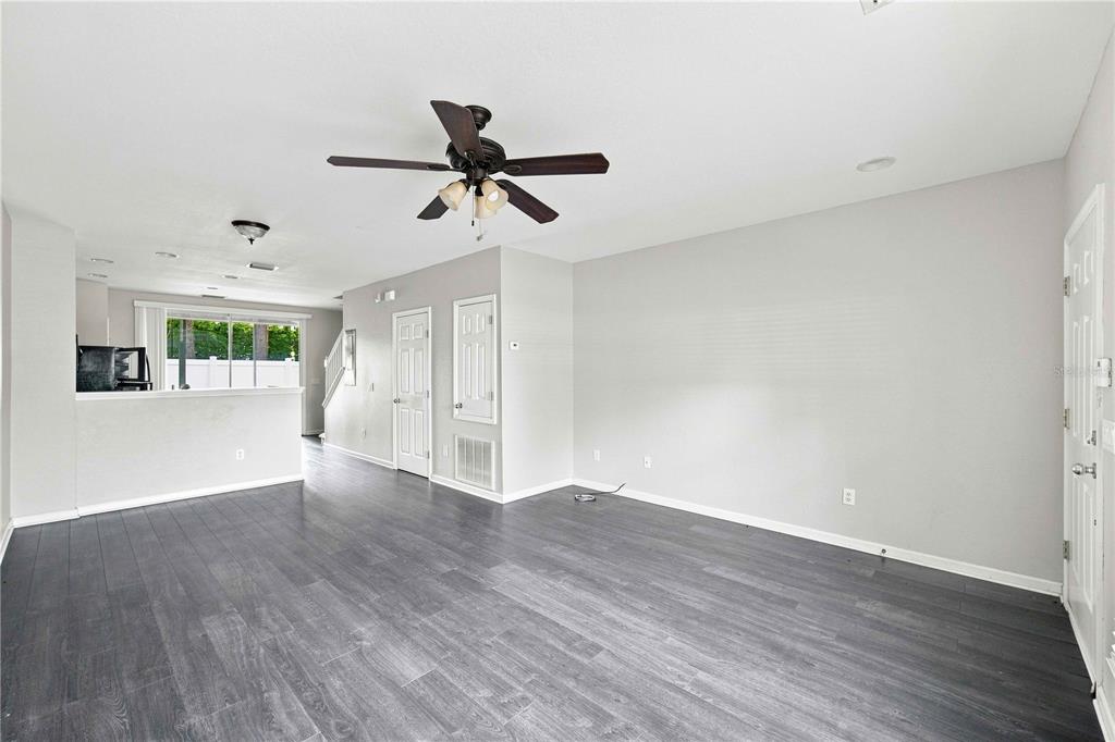 An open-concept living area features gray wood-look flooring, a ceiling fan, and white walls — 4434 SW 49TH AVENUE, OCALA, FL