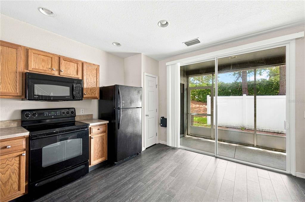 A kitchen with wood cabinets, black appliances, and a sliding door leading to a screened patio — 4434 SW 49TH AVENUE, OCALA, FL