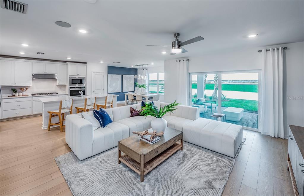 An open-concept living room and kitchen feature white cabinetry, a sectional sofa, and sliding doors — 4809 FINLEY DRIVE, DAVENPORT, FL