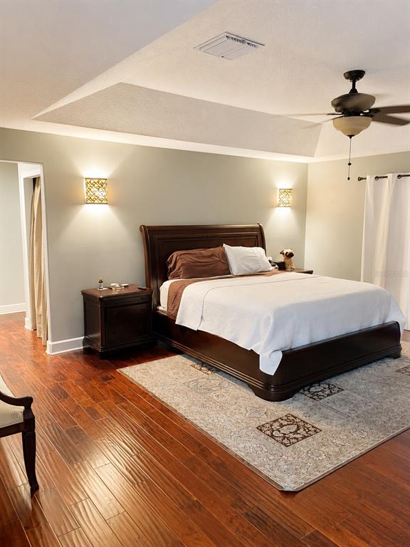 A bedroom features a dark wood sleigh bed, hardwood floors, and two wall-mounted sconces — 2927 CURVING OAKS WAY, ORLANDO, FL