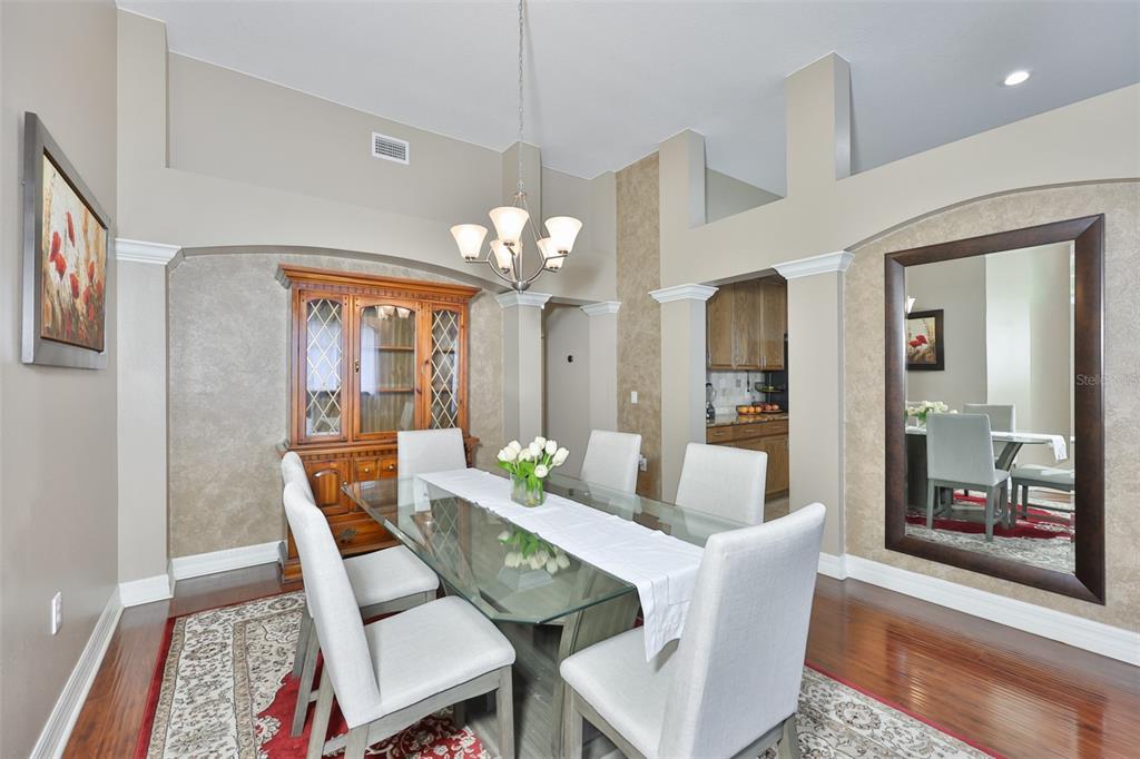 A dining room features a glass-top table, upholstered chairs, a hutch, and a large mirror — 7318 GUILFORD PINE LANE, APOLLO BEACH, FL