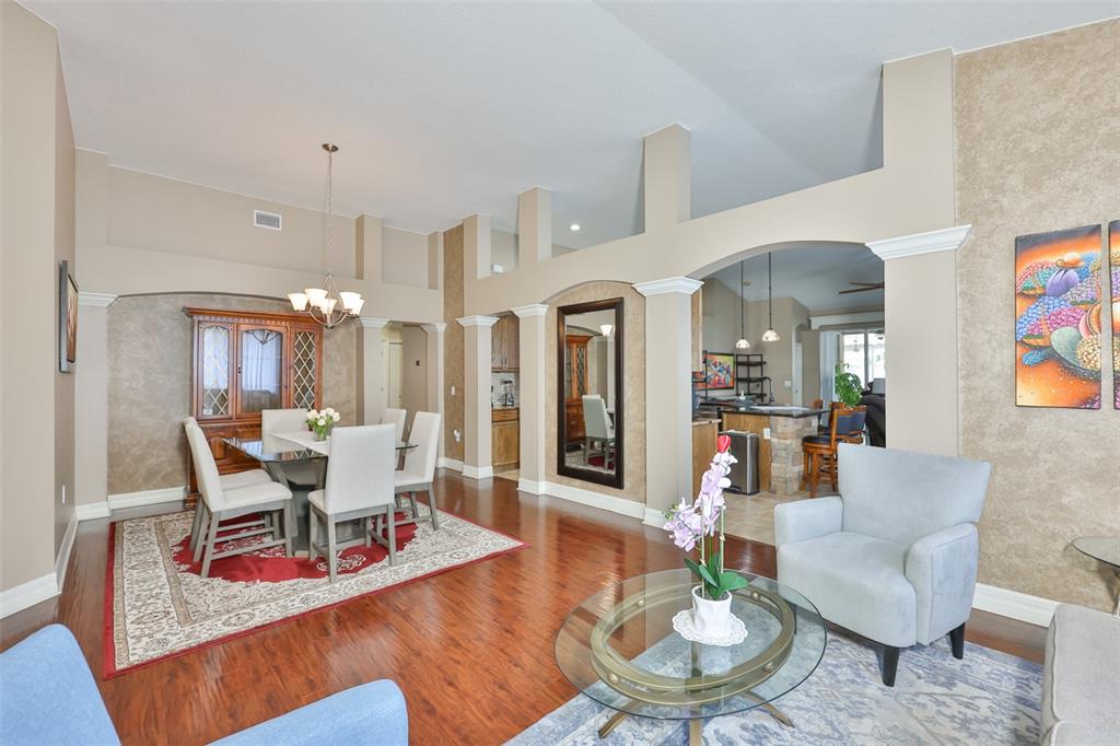 A dining area and living space feature hardwood floors, vaulted ceilings, and arched architectural details — 7318 GUILFORD PINE LANE, APOLLO BEACH, FL