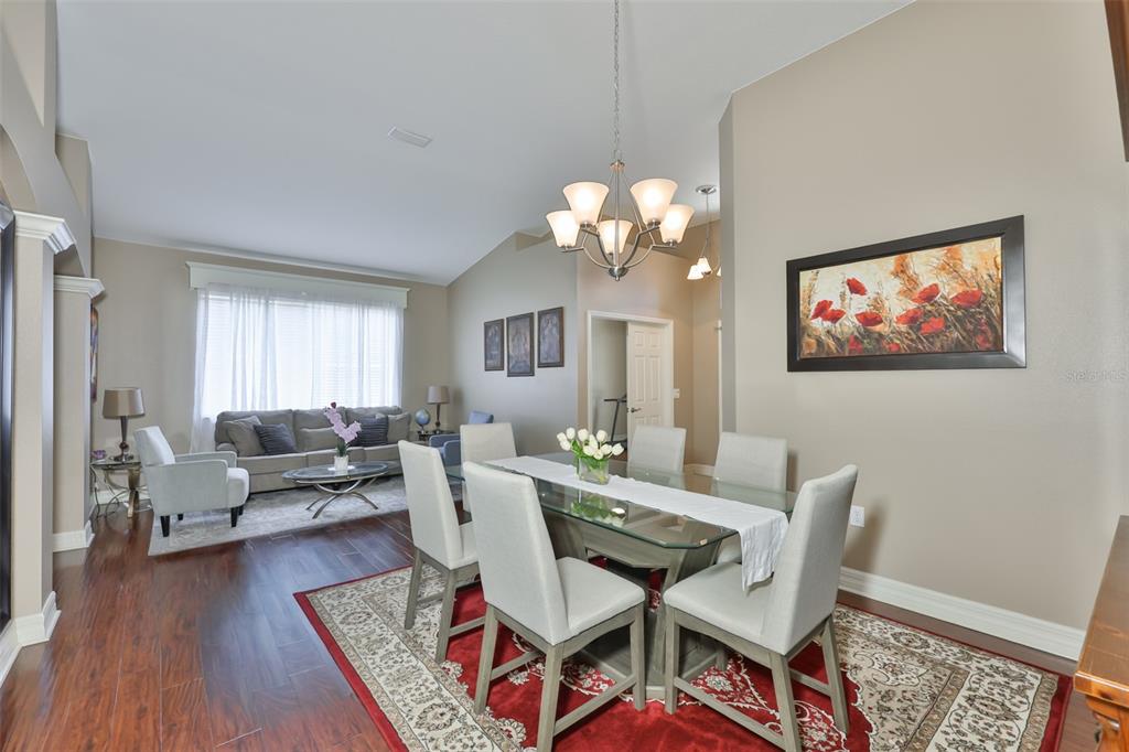 A dining area with a glass table and chairs sits adjacent to a living room — 7318 GUILFORD PINE LANE, APOLLO BEACH, FL