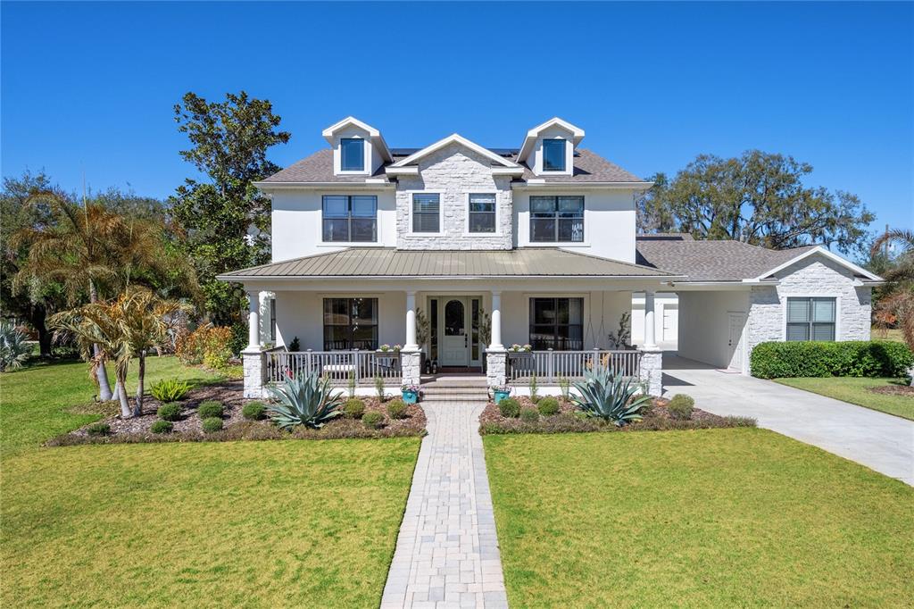 A two-story house with a white exterior, stone accents, a front porch, and a walkway — 5351 CARSON STREET, ST CLOUD, FL