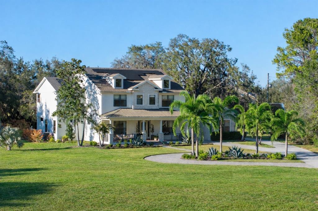 A two-story white house with a covered porch sits on a large grassy lawn — 5351 CARSON STREET, ST CLOUD, FL