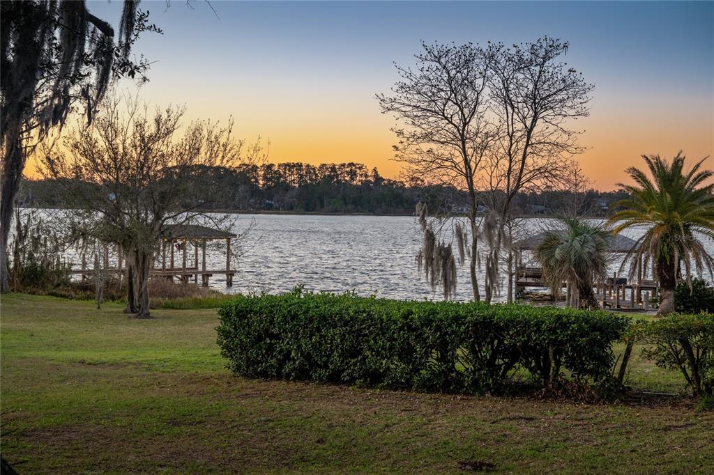 A grassy yard overlooks a lake with two boat docks at sunset — 5351 CARSON STREET, ST CLOUD, FL
