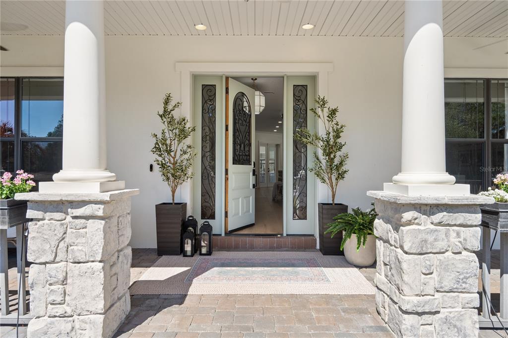 A front porch features stone columns, a light-colored door with glass inserts, and potted plants — 5351 CARSON STREET, ST CLOUD, FL