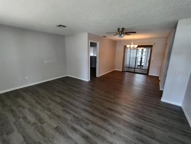 A spacious living room features gray wood-look flooring, a ceiling fan, and sliding glass doors — 9180 SW 101ST PLACE, OCALA, FL