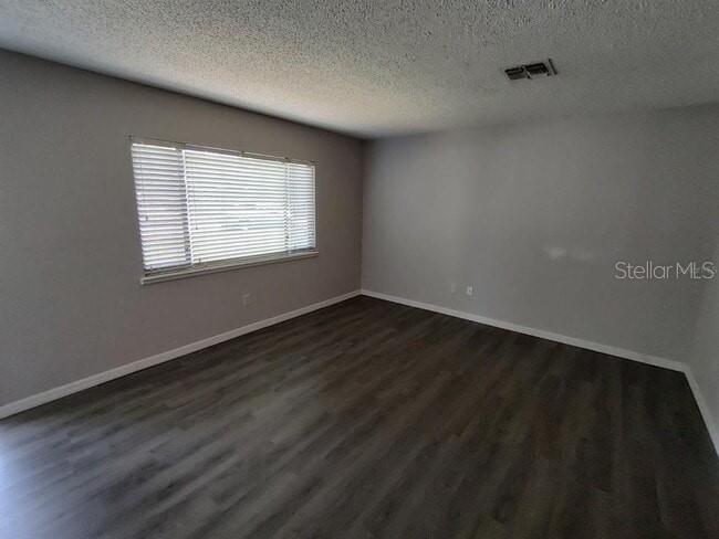 An empty room features gray walls, dark wood-look flooring, and a window with white blinds — 9180 SW 101ST PLACE, OCALA, FL