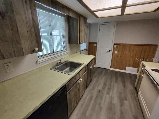 A kitchen features wood-look cabinets, a light green countertop, and wood-paneled walls — 9180 SW 101ST PLACE, OCALA, FL