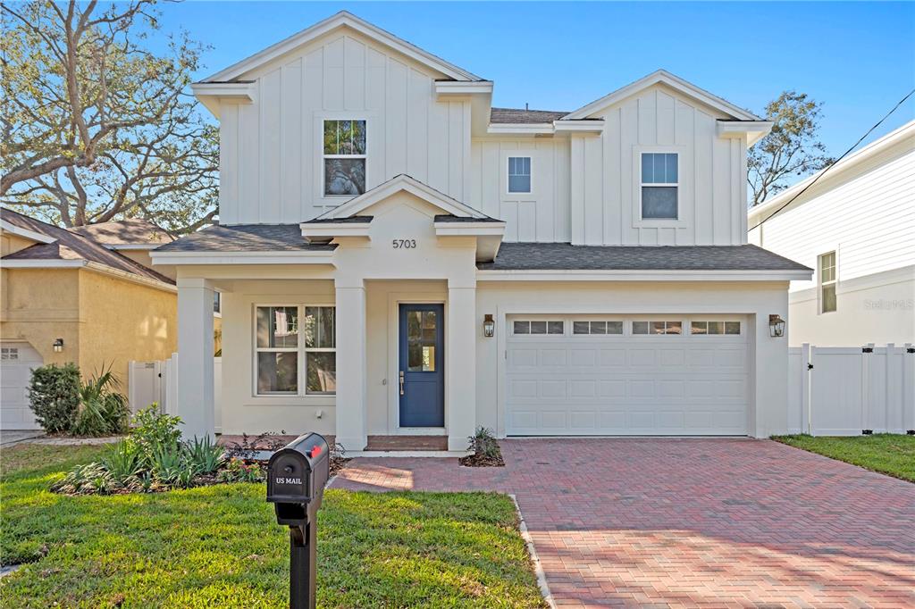 A two-story white house with a blue front door and a brick driveway — 4314 S RENELLIE DRIVE, TAMPA, FL
