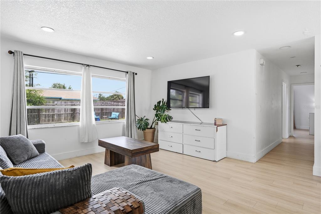 A living room features light wood flooring, a gray sectional sofa, and a wall-mounted television — 835 MARLOWE AVENUE, ORLANDO, FL
