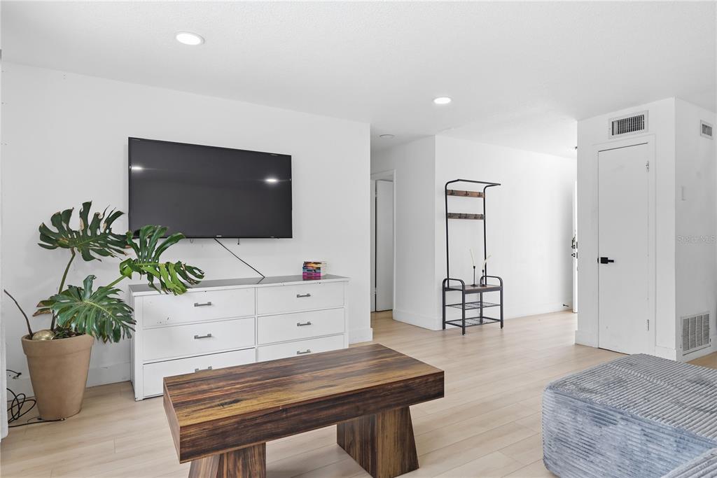 A living room features light wood flooring, white walls, a television, and a wooden coffee table — 835 MARLOWE AVENUE, ORLANDO, FL