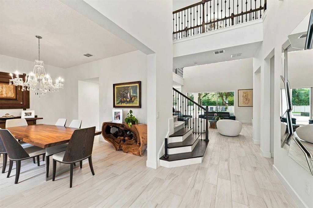 A dining room with a wooden table leads into a foyer with a staircase — 1113 HOLSTONS POINTE PLACE, GOTHA, FL