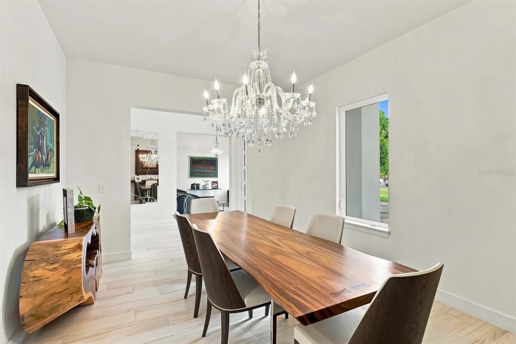 A dining room features a live-edge wood table, a crystal chandelier, and light tile flooring — 1113 HOLSTONS POINTE PLACE, GOTHA, FL
