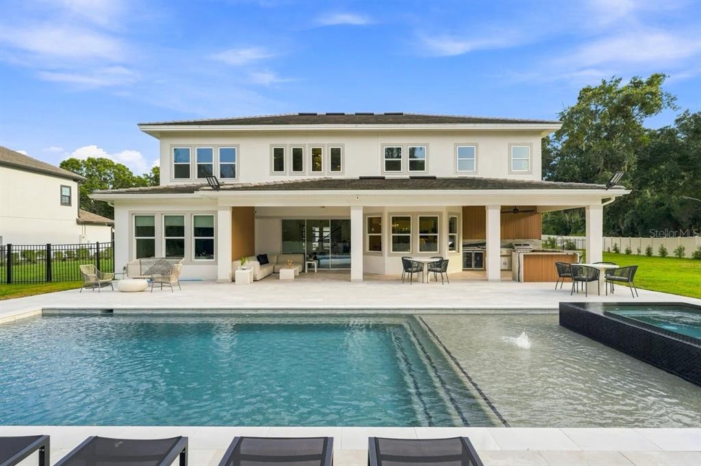 A bright, open-concept living room with black leather sofas, a wood-base coffee table, and pool views — 1113 HOLSTONS POINTE PLACE, GOTHA, FL