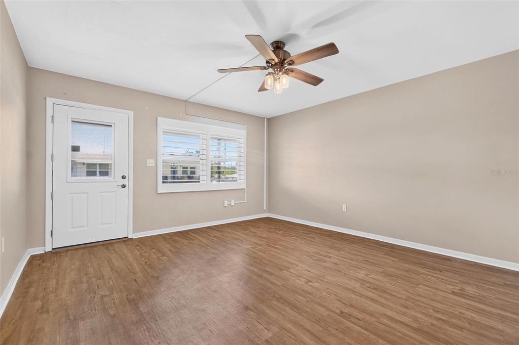 An empty room features light brown wood-look flooring, beige walls, and a ceiling fan — 138 36TH AVENUE N UNIT 208 W, ST PETERSBURG, FL