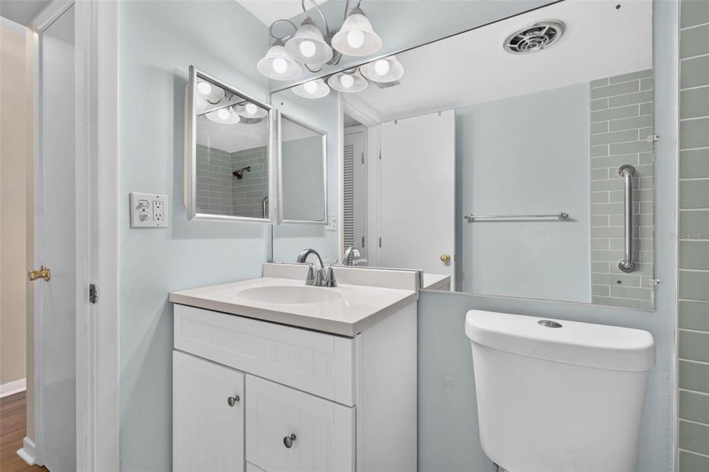 A bathroom features a white vanity, a mirror, a toilet, and light blue wall paint — 138 36TH AVENUE N UNIT 208 W, ST PETERSBURG, FL
