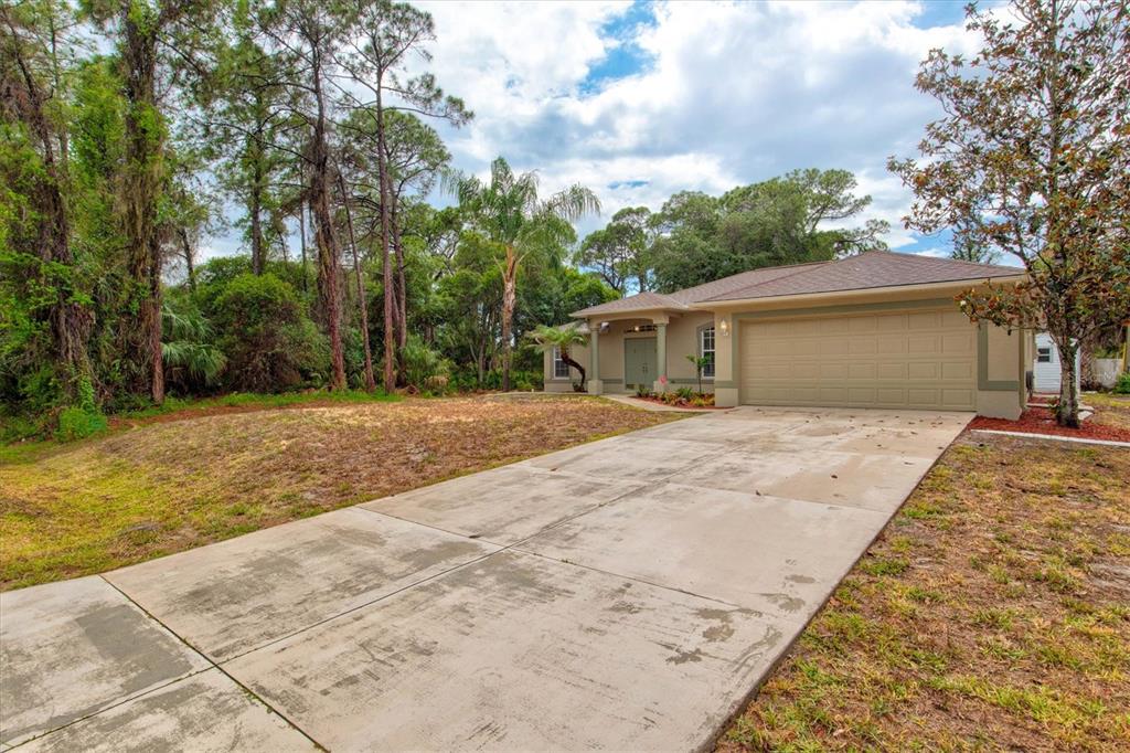 A single-story house with a beige exterior and a two-car garage sits on a lot — 5047 ADINA CIRCLE, NORTH PORT, FL
