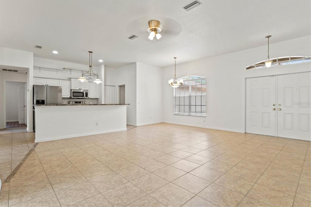 An open-concept living area features tile flooring, a kitchen with white cabinets, and double doors — 5047 ADINA CIRCLE, NORTH PORT, FL