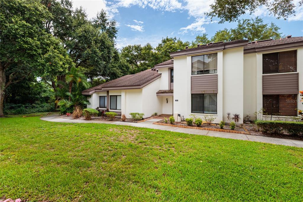 A view of a grassy courtyard between two multi-story apartment buildings with sidewalks — 1750 LAKE CYPRESS DRIVE UNIT 1002, SAFETY HARBOR, FL