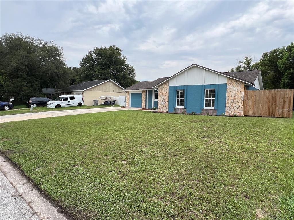 A single-story house with blue siding, stone accents, and a large front lawn — 6 E THRUSH STREET, APOPKA, FL