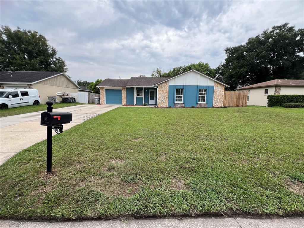 A single-story house with blue siding, stone accents, a garage, and a large front lawn — 6 E THRUSH STREET, APOPKA, FL